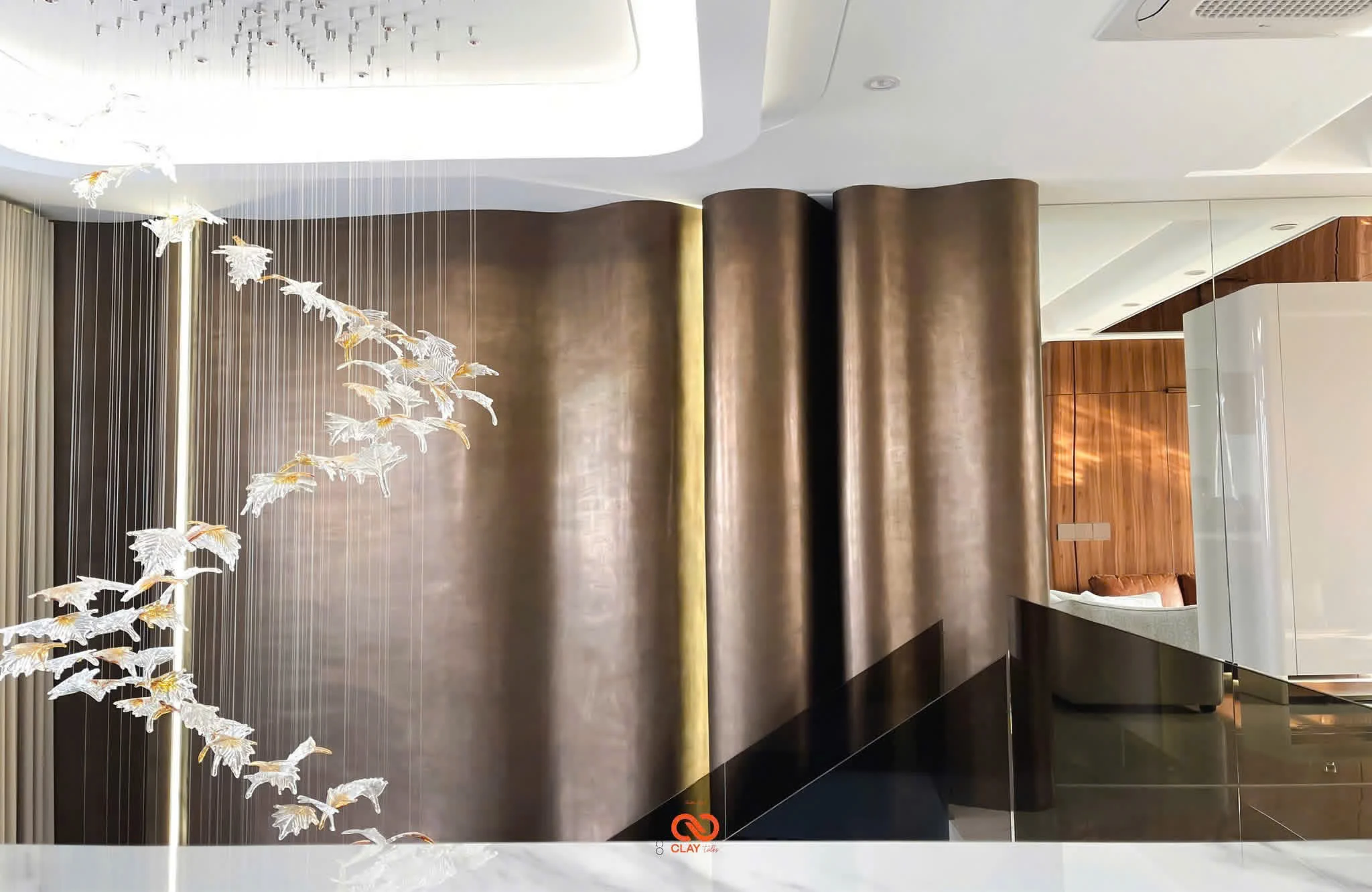 A real bronze-finish interior wall with a hanging glass bird chandelier.